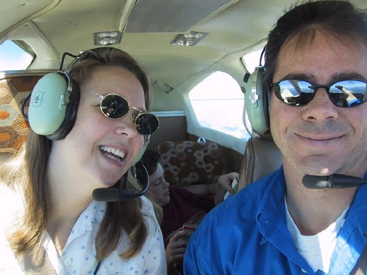 Mike and Debbie in the front seats of an airplane, with son Chris behind them
