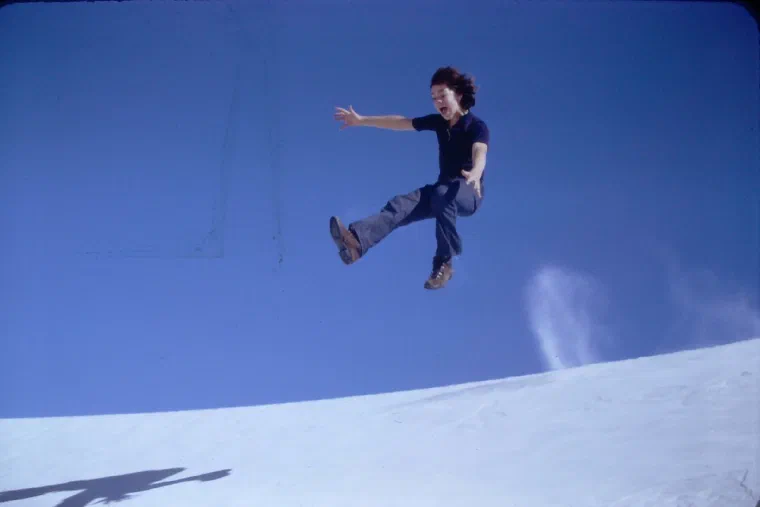 A person jumping above a white sand dune