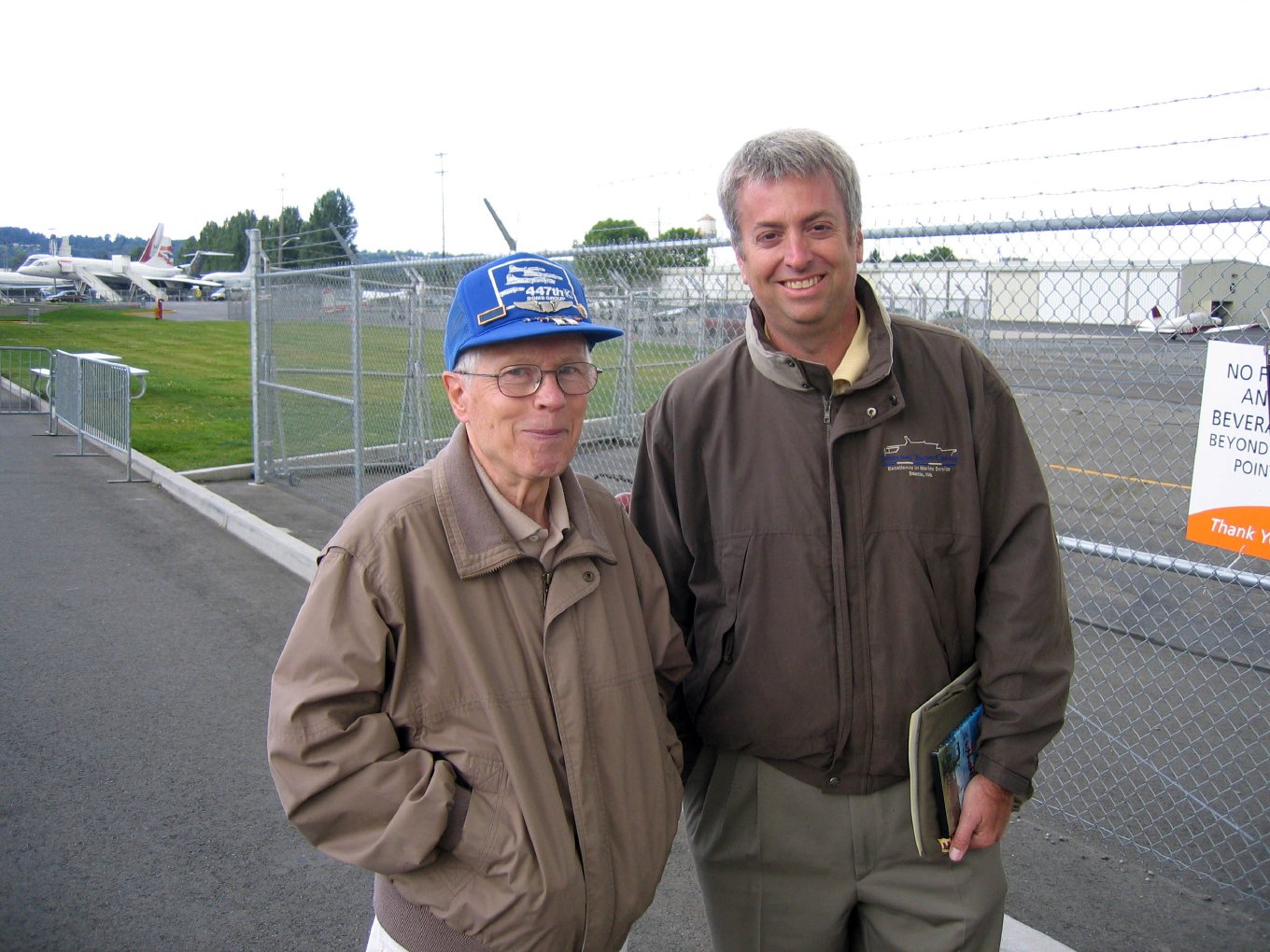 Dick Nelms, in a blue cap, standing by the airfield fence after the flight