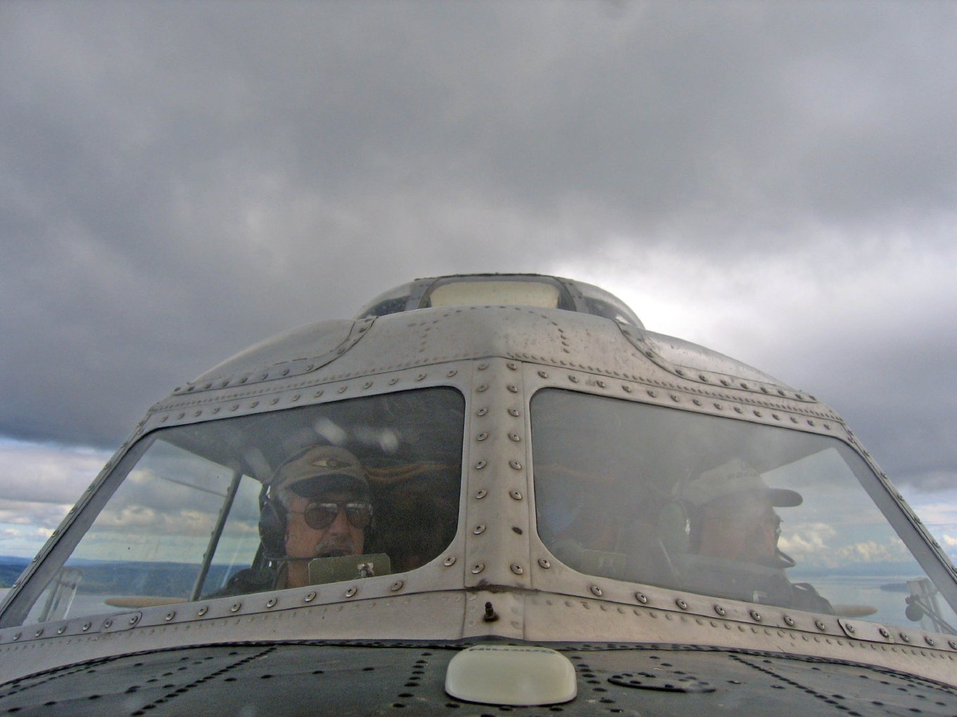 The pilots' windows seen from below, under a cloudy sky
