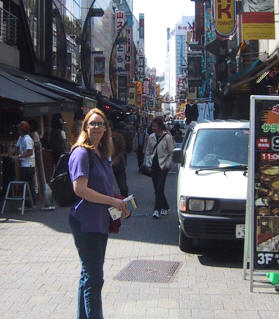 Deb on a busy market street lined with shop signs