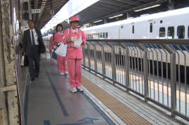 Women in pink uniforms waiting on the Shinkansen platform