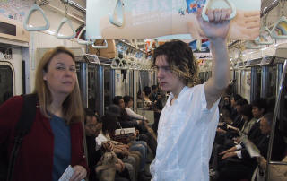 Deb and Chris standing in a crowded subway car, Chris holding a strap