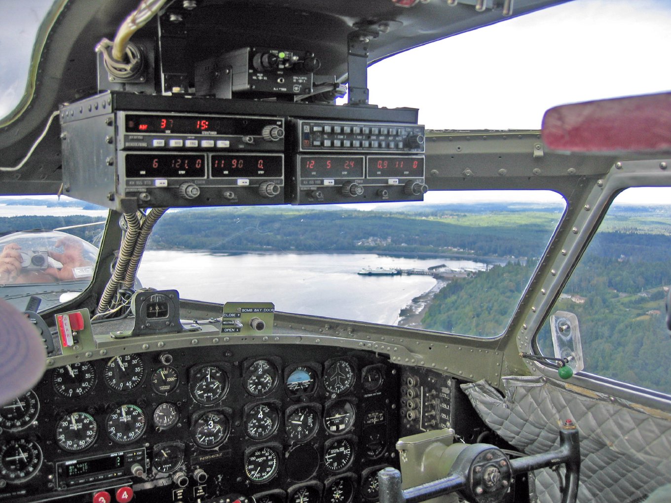 The view through the cockpit windows of a B-17, over the water and shoreline of Puget Sound