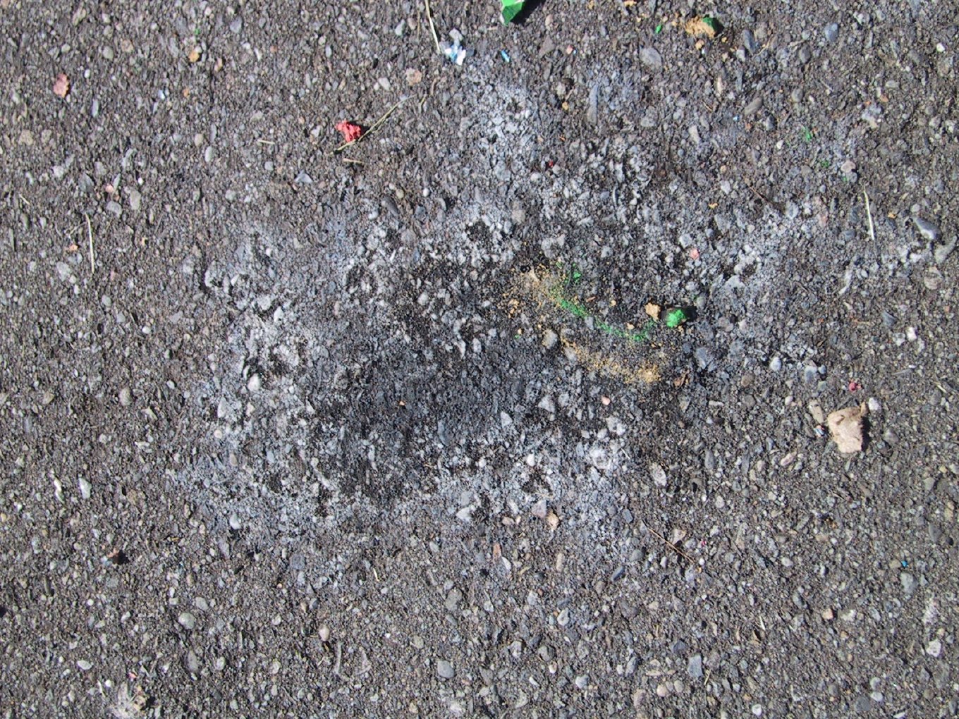 Scorch marks and firework debris on a gravel driveway